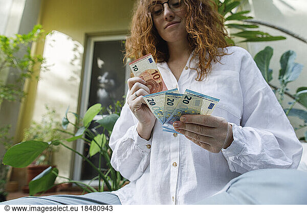 Woman counting paper currency in backyard