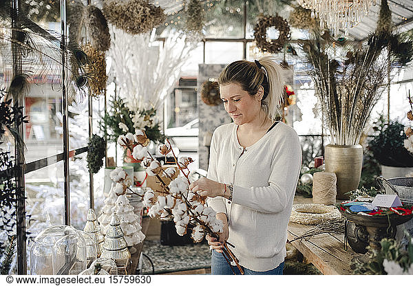 Woman creating Christmas decor arrangement in shop