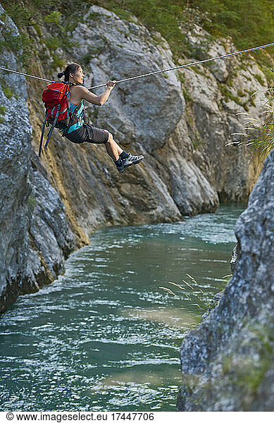 Woman crossing river on Tyrolean traverse in the Verdon canyon