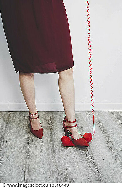 Woman crushing red telephone receiver with red heels