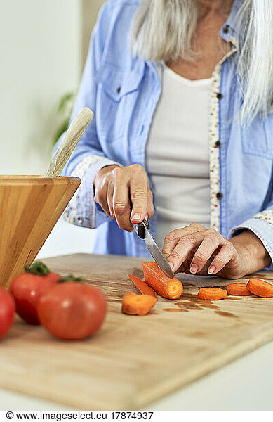 Woman cutting carrots in kitchen