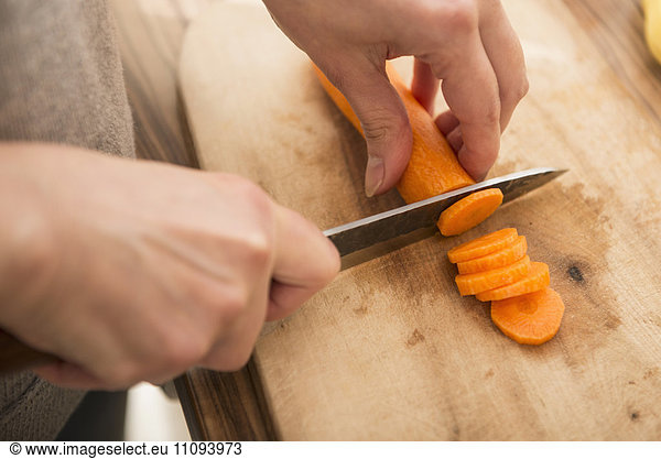 Woman cutting carrots on cutting board in kitchen