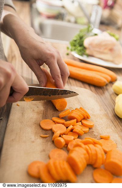 Woman cutting carrots on cutting board in kitchen