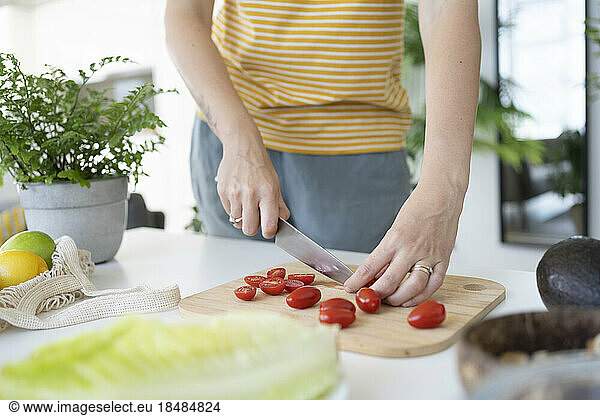 Woman cutting cherry tomatoes at home