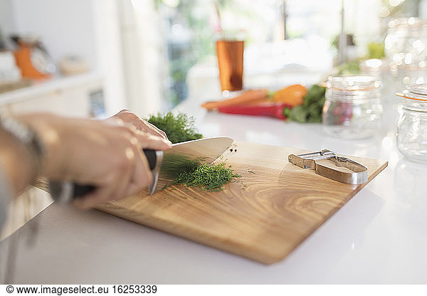 Woman cutting fresh dill on cutting board