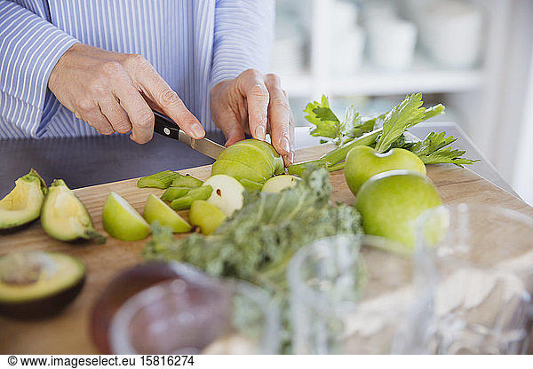 Woman cutting healthy green apples and produce on cutting board