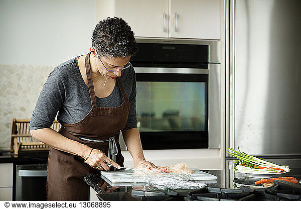 Woman cutting meat on cutting board