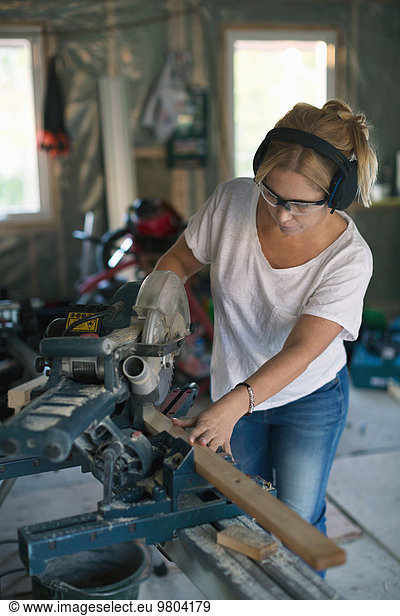Woman cutting wood with circular saw during home improvement