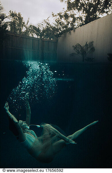 Woman dancer falling through deep dark blue water