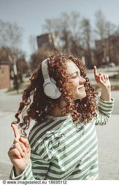Woman dancing and listening to music through bluetooth headphones