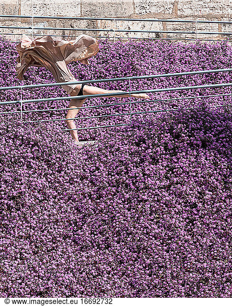 Woman dancing surrounded by purple flowers with a flying dress