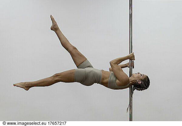 Woman dancing suspended in the air holding hands on pole dance