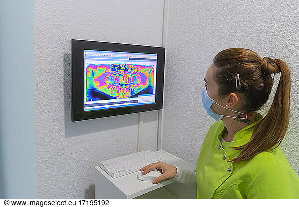 Woman dentist with mask analyzing an x-ray scan in dental clinic