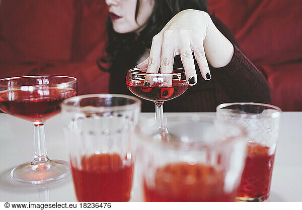 Woman dipping fingers inside red alcohol drink