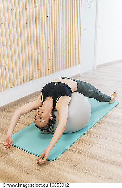 Woman doing a relaxation exercise with fitness ball at health club