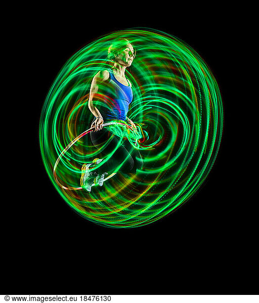 Woman doing exercise with hula hoops against black background
