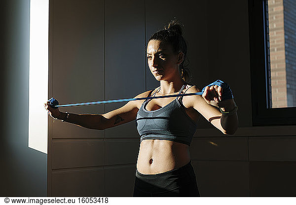 Woman doing exercising with fitness band at home