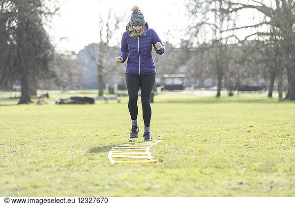 Woman doing speed ladder drill in sunny park
