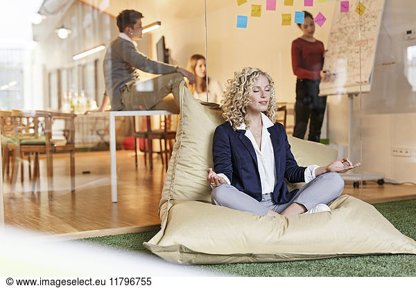 Woman doing yoga in bean bag with meeting in background