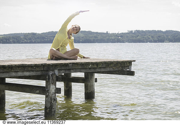Woman doing yoga on boardwalk at the lake  Ammersee  Upper Bavaria  Germany