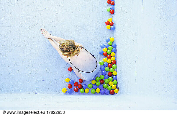 Woman doing yoga sitting by multi colored balls in empty swimming pool