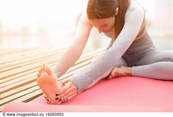 Woman doing yoga stretching on summer park.