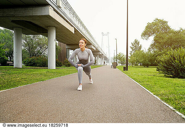 Woman dressed leggings and top running asphalt road summer park.