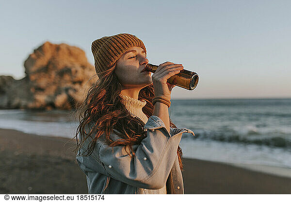 Woman drinking beer at beach