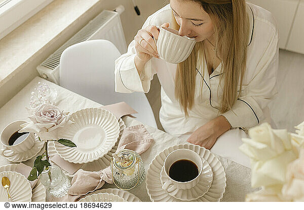 Woman drinking black coffee sitting at table in home