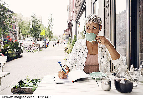 Woman drinking coffee at sidewalk cafe