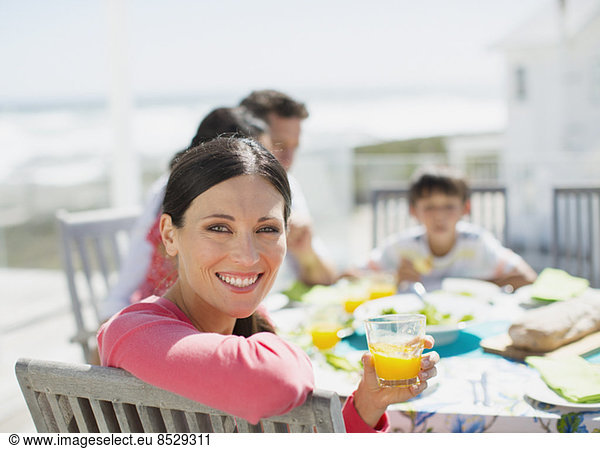 Woman drinking orange juice at table on sunny patio