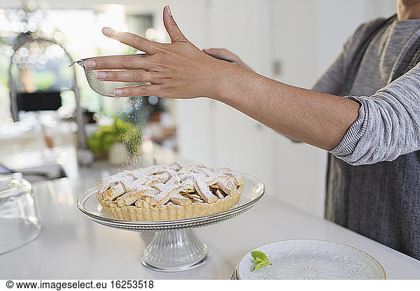 Woman dusting homemade pie with powdered sugar