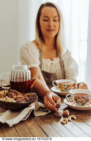 Woman eating dry fruits  figs and nuts and drinking hibiscus tea