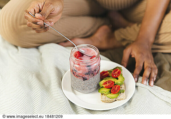 Woman eating healthy breakfast on bed