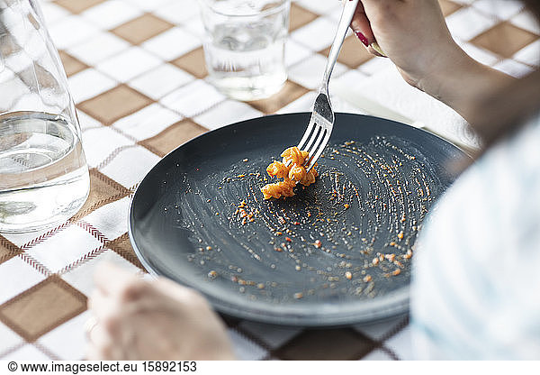 Woman eating last pasta from plate