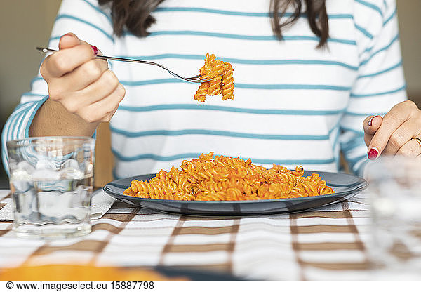 Woman eating pasta at dining table at home