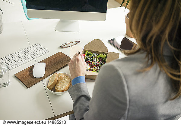 Woman eating salad for lunch at her desk