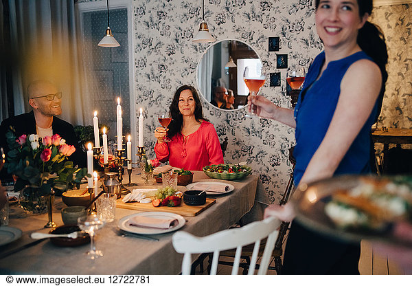 Woman enjoying drinks with friends at dining table in party
