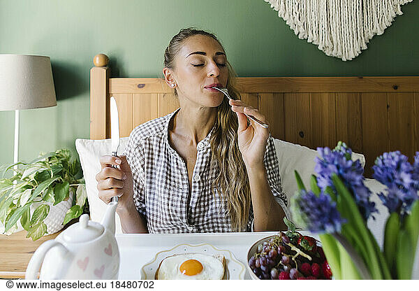 Woman enjoying morning breakfast in bed at home