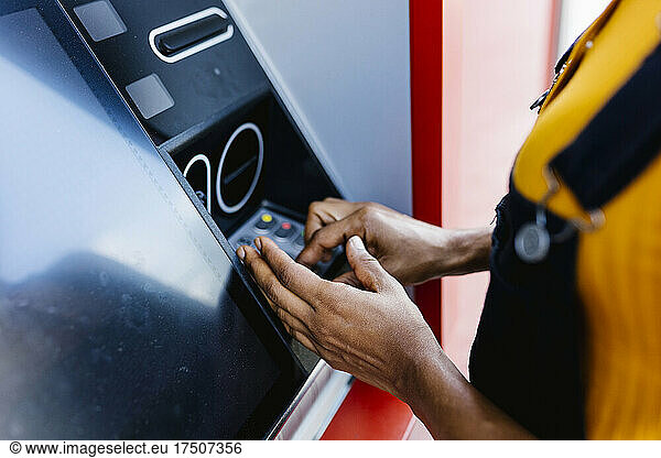 Woman entering pin in ATM machine
