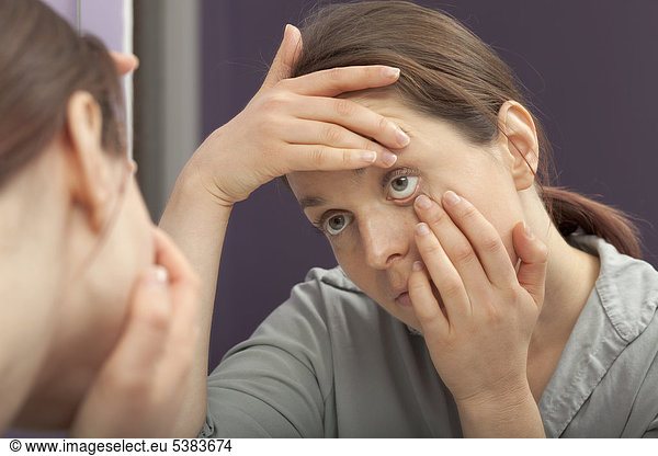 Woman examining her eye in the mirror