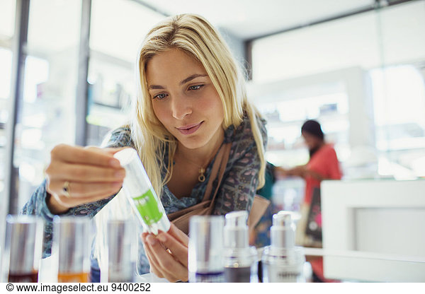 Woman examining skincare product in drugstore