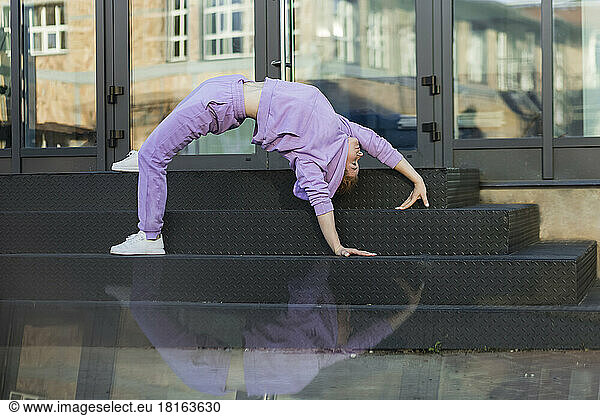 Woman exercising bridge position on staircase in front of glass door