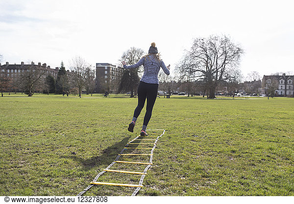 Woman exercising  doing speed ladder drill in sunny park