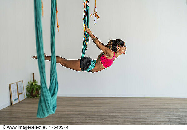 Woman exercising on aerial silk in yoga studio