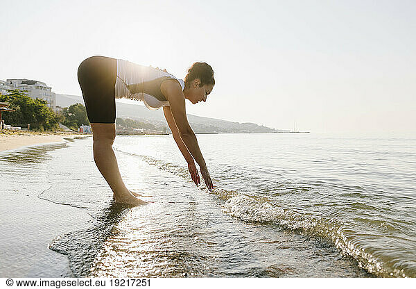 Woman exercising on coastline at beach