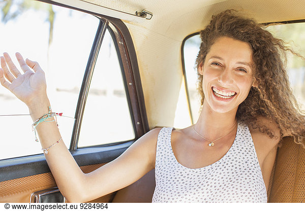 Woman feeling breeze from backseat car window