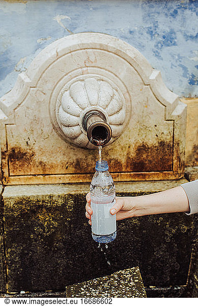 Woman filling plastic bottle with spring water