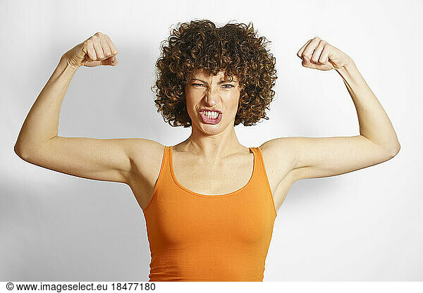 Woman flexing muscles against white background