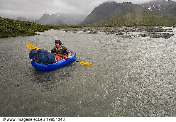 Woman floating down a river in a very small raft in Denali National Park  Alaska.